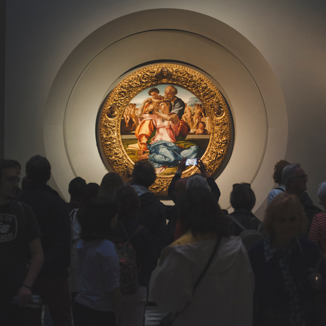 People crowded around a painting with ornate gold frame